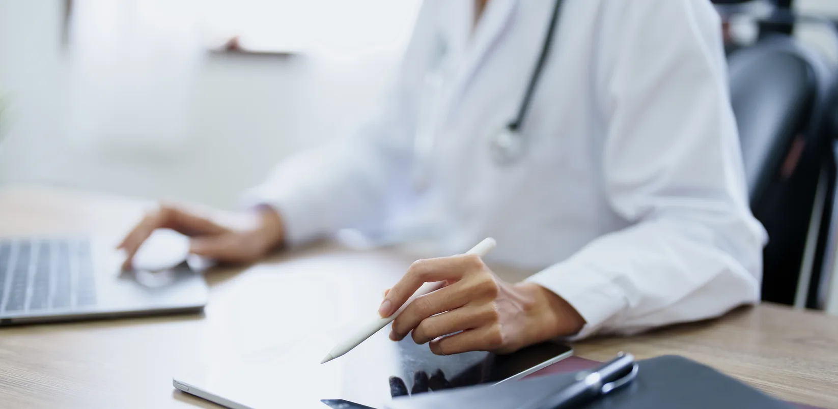 Médico trabajando con un portátil en su consulta